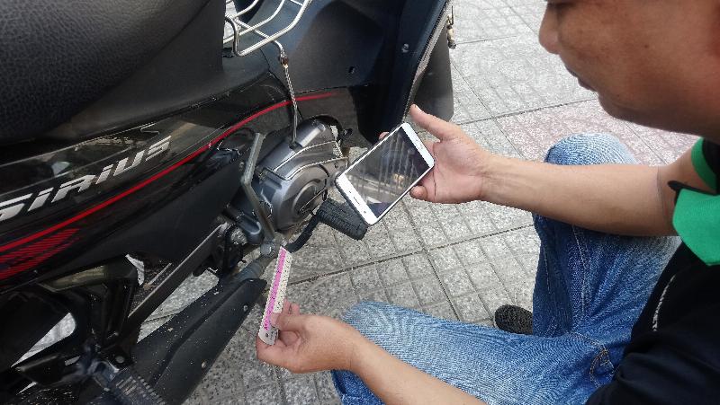 Một người đàn ông đang cẩn thận kiểm tra động cơ của chiếc xe Cub 50 cũ, thể hiện bước quan trọng khi mua xe và ảnh hưởng đến giá xe cub 50 cũ.